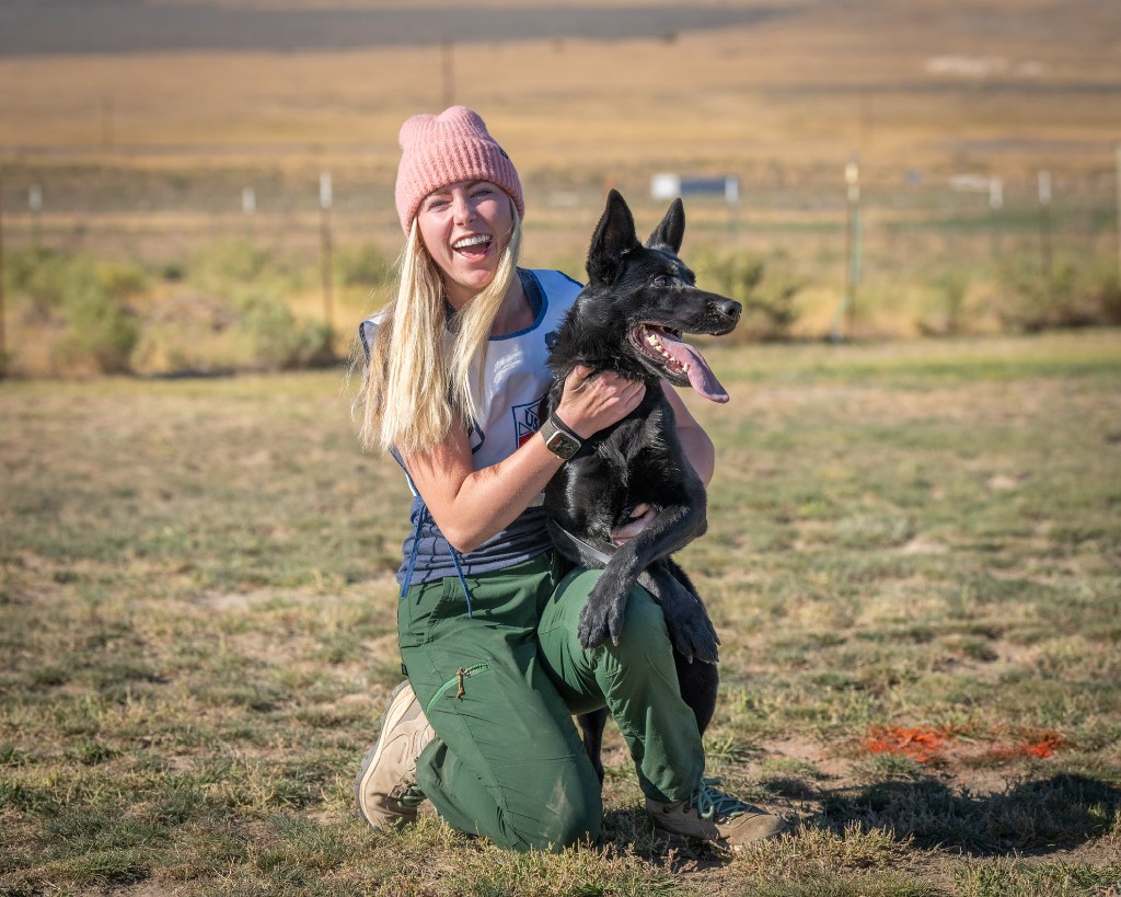 Ashley smiling with a black dog at the ranch